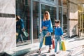 Sale consumerism and people concept - happy young women her dauther with shopping bags walking city street Royalty Free Stock Photo