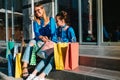 Beautiful mom and her cute little daughter are holding shopping bags, looking at camera and smiling while standing outdoors. Royalty Free Stock Photo