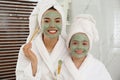 Young mother and daughter with facial masks in bathroom Royalty Free Stock Photo
