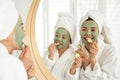 Young mother and her daughter with masks near mirror in bathroom Royalty Free Stock Photo