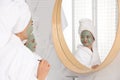 Young mother and her daughter with facial masks near mirror in bathroom Royalty Free Stock Photo