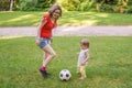 Young mother and her daughter have a fun. Woman and child are playing with ball in park Royalty Free Stock Photo