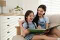 Young mother and her daughter reading book on sofa at home, space for text Royalty Free Stock Photo