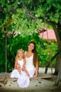 Young mother and her daughter swinging at tropic