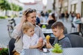 Young mother with her kids eating ice-cream in cafe outdoors in street in summer. Royalty Free Stock Photo