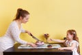 A young mother and her little daughter cutting a cake for a birthday party Royalty Free Stock Photo