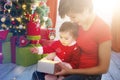 Young mother and her little daughter dressed as santa claus opening a magical Christmas gift by a Christmas tree in cozy Royalty Free Stock Photo