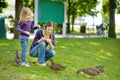 Young mother and her little daughter feeding ducks on summer day. Child feeding birds outdoors Royalty Free Stock Photo