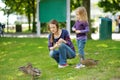 Young mother and her little daughter feeding ducks on summer day. Child feeding birds outdoors Royalty Free Stock Photo