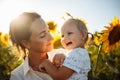 Young mother and her little daughter having fun and enjoy life at the sunflower field on a bright sunny summer day. Summer holiday Royalty Free Stock Photo