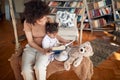 A young mother and her little daughter sitting on the swing at home and enjoying while reading a book together. Family, together, Royalty Free Stock Photo