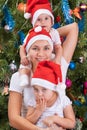 Young mother and her little daughters near to a Christmas tree Royalty Free Stock Photo