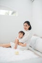 Young mother with her little girl are relaxing and playing in the bed at the weekend together. Kid at home concept Royalty Free Stock Photo