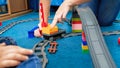 Young mother with her little playing a game with trains and railroad on floor