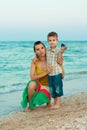 Young mother with her son on the beach with shell
