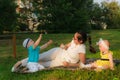 A young mother with her son and daughter lie on the grass and are happy with soap bubbles