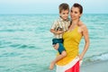 Young mother with her son goes on the beach