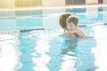 Young mother and her son having fun in a swimming pool. Healthy family mother teaching baby swimming pool Royalty Free Stock Photo