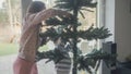 Young mother and her son making an artificial christmas tree
