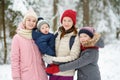 Young mother and her three kids having fun outdoors. Two young girls and their baby boy sibling on winter day. Kids with large age