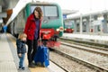 Young mother and her toddler son on a railway station. Mom and little child waiting for a train on a platform. Family with a Royalty Free Stock Photo