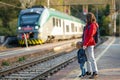 Young mother and her toddler son on a railway station. Mom and little child waiting for a train on a platform. Family ready to Royalty Free Stock Photo