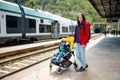 Young mother and her toddler son on a railway station. Mom and little child waiting for a train on a platform. Family ready to Royalty Free Stock Photo