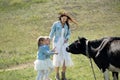 Young mother and her twin daughters feed a black cow in a meadow in the village Royalty Free Stock Photo