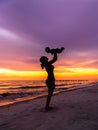 Young mother holding baby above head on beach with sunset background