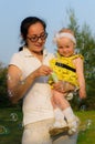 A young mother holding a baby and blowing bubbles