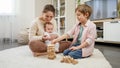 Young mother holding baby boy and playing with her older son in wooden blocks. Parenting, children happiness and family Royalty Free Stock Photo