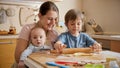 Young mother holding baby helping older son baking pizza at home. Children cooking with parents, little chef, family Royalty Free Stock Photo