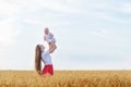 Young mother holding baby in her arms in wheat field. Vacation with children in countryside Royalty Free Stock Photo