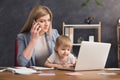 Young mother holding baby while talking on phone