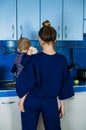 Young mother holding cute baby daughter in kitchen. Happy family mother and baby toddler girl cooking food at home Royalty Free Stock Photo