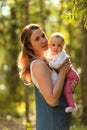 Young mother holding daughter in her arms. mom kisses and plays with daughter in the summer. Happy family in the park Royalty Free Stock Photo