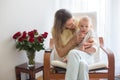 Young mother holding her baby boy, playing with him, sitting in