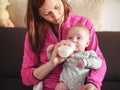 Young mother holding her infant baby son on her hands, feeding him milk from bottle Royalty Free Stock Photo