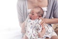 Young mother holding her newborn baby girl, one week daughter. Using blanket wrap baby body