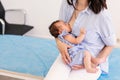 Young mother holding her newborn child. Mom nursing baby. Woman and new born boy relax in a white bedroom. Mother breast feeding Royalty Free Stock Photo