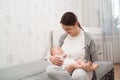 Young mother holding her newborn child. Mom nursing baby. Woman and new born boy relax in a white bedroom. Royalty Free Stock Photo