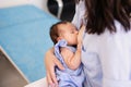 Young mother holding her newborn child. Mom nursing baby. Woman and new born boy relax in a white bedroom. Mother breast feeding Royalty Free Stock Photo