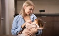 Young mother holding her newborn child. Mom nursing baby. Woman and new born boy relax in a white bedroom with rocking Royalty Free Stock Photo