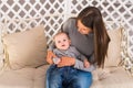 Young mother holding her newborn child. Mom nursing baby. Woman and new born boy in the room. Mother playing with Royalty Free Stock Photo