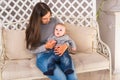 Young mother holding her newborn child. Woman and baby boy relax in a white bedroom. Nursery interior. Family at home Royalty Free Stock Photo