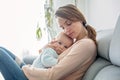 Young mother, holding her sick toddler boy, hugging him at home