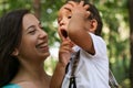 Young mother holding her yawning son at hands of the Park