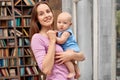 Baby Care. Young mother standing holding little son at home posing to camera cheerful holding hands