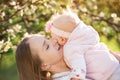 Young mother holds a baby on the flowering trees background. Mother`s love and tenderness