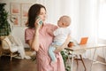 A young mother holds a baby in her arms and talks on the phone Royalty Free Stock Photo